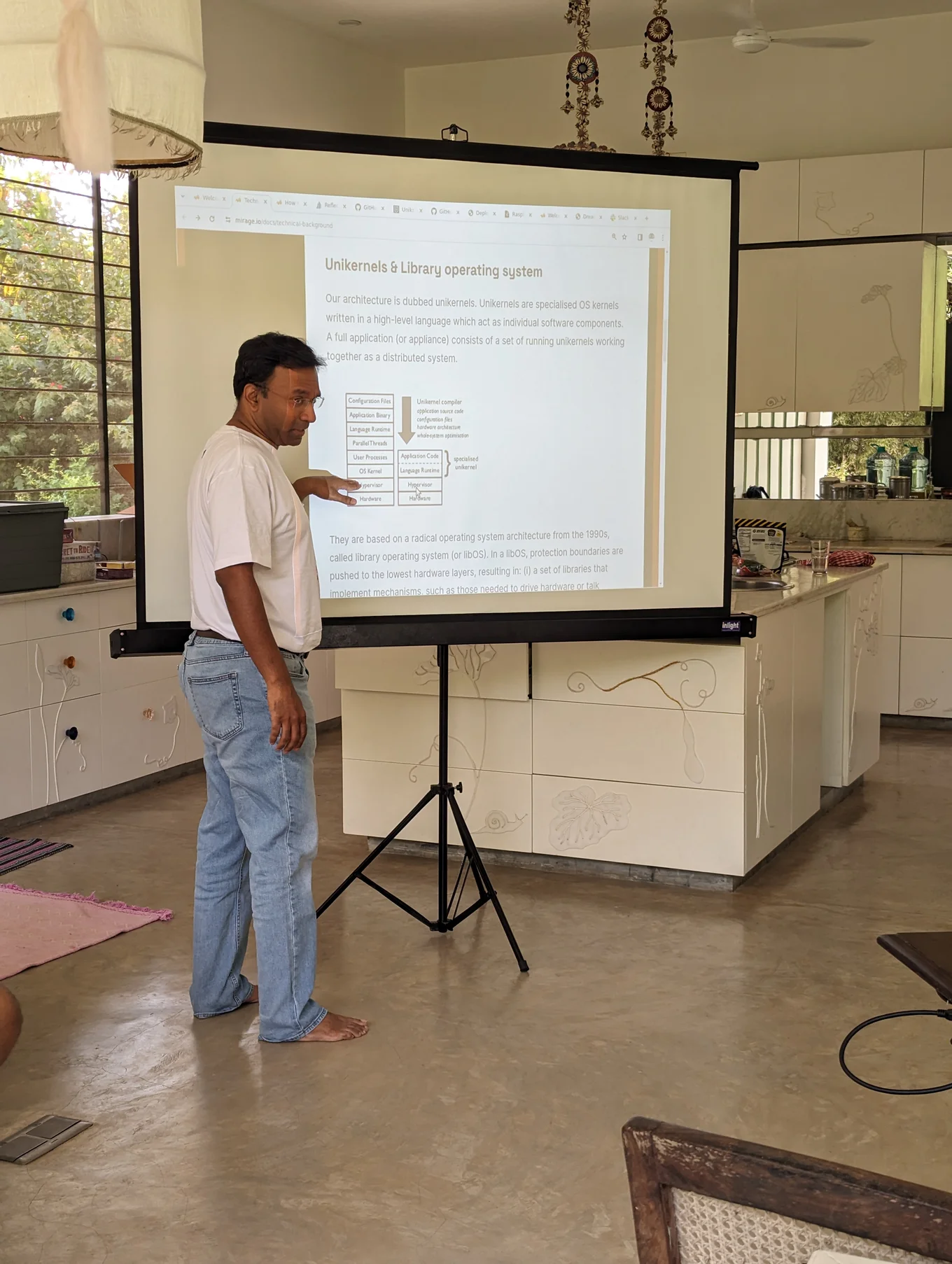 One of the participants is giving a talk standing in front of a projector screen with the text "unikernels and library operating system".