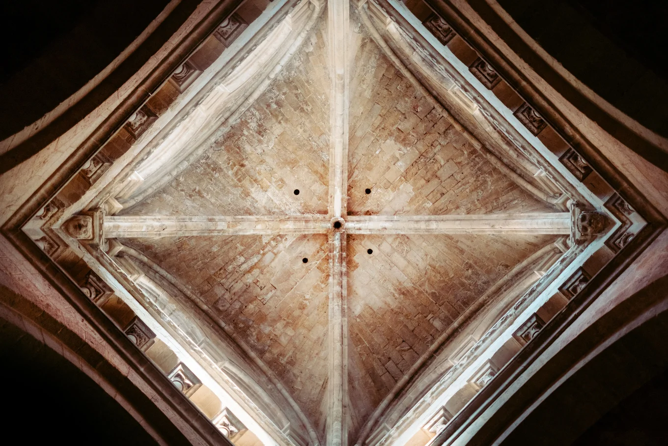 Stone cathedral ceiling with four central beams.