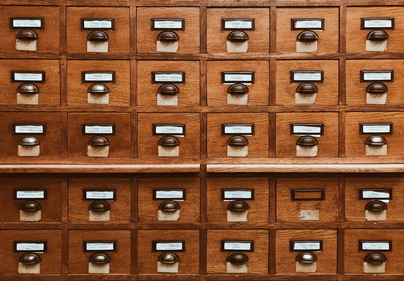 Wooden file cabinet with labeled drawers.