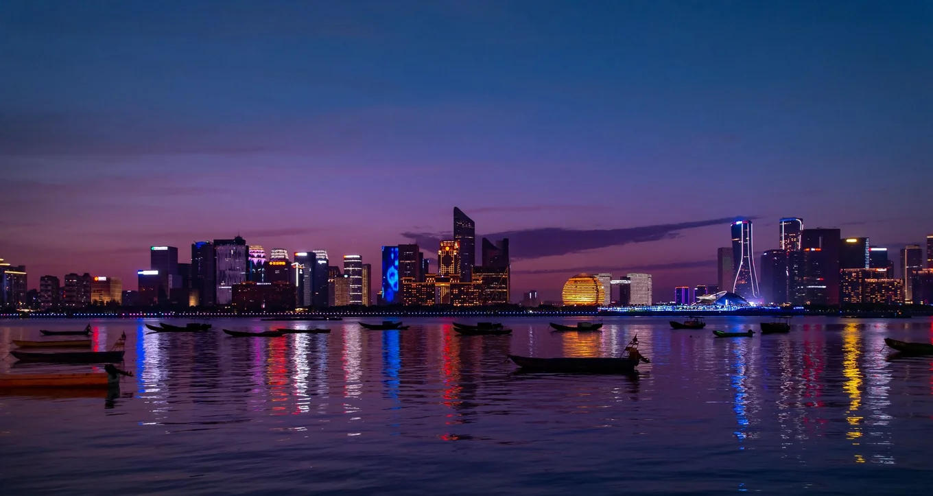 City skyline, dusk, illuminated buildings, reflections.