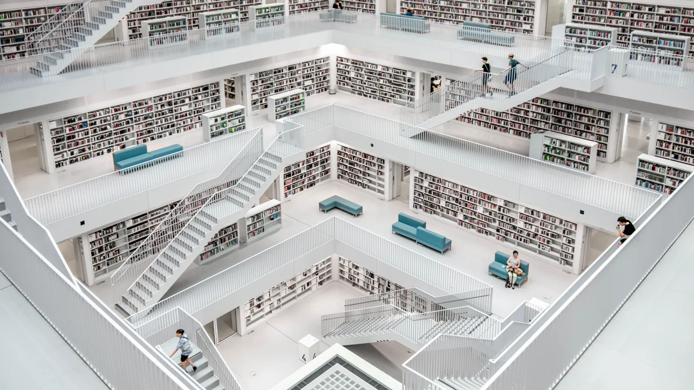 Modern library, staircases, bookshelves, people, seating.