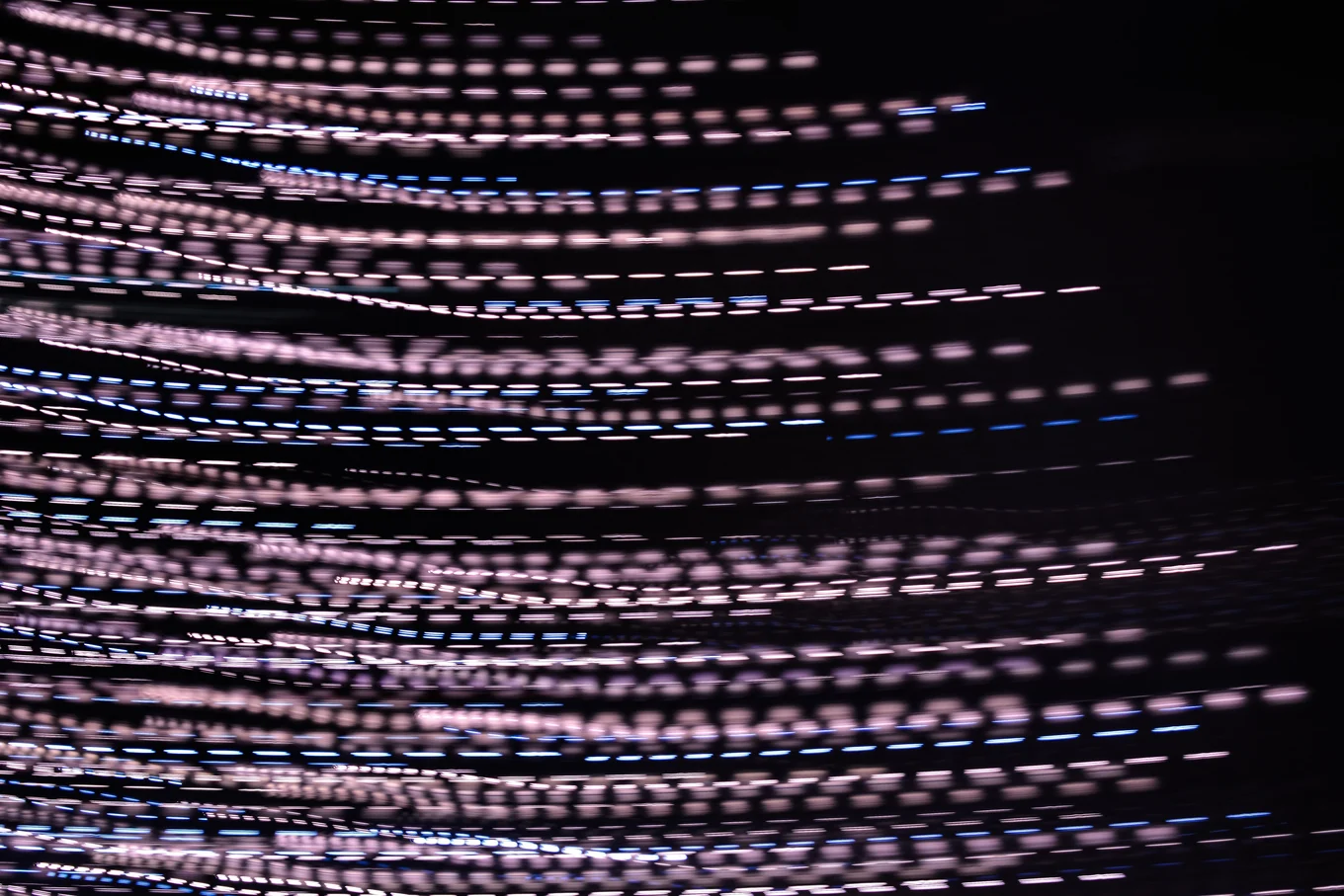 Blurred pink and blue light streaks on black background.