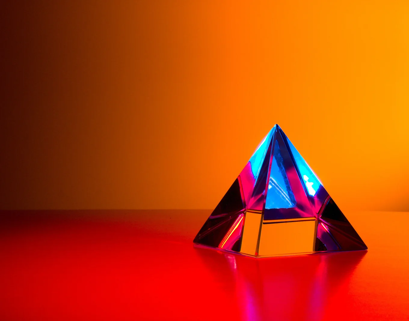 Glass pyramid with colorful lights, red surface.